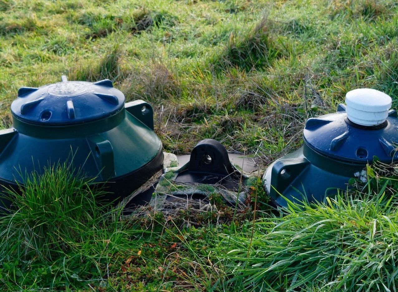 Deux conteneurs verts sont posés dans l'herbe dans un champ.