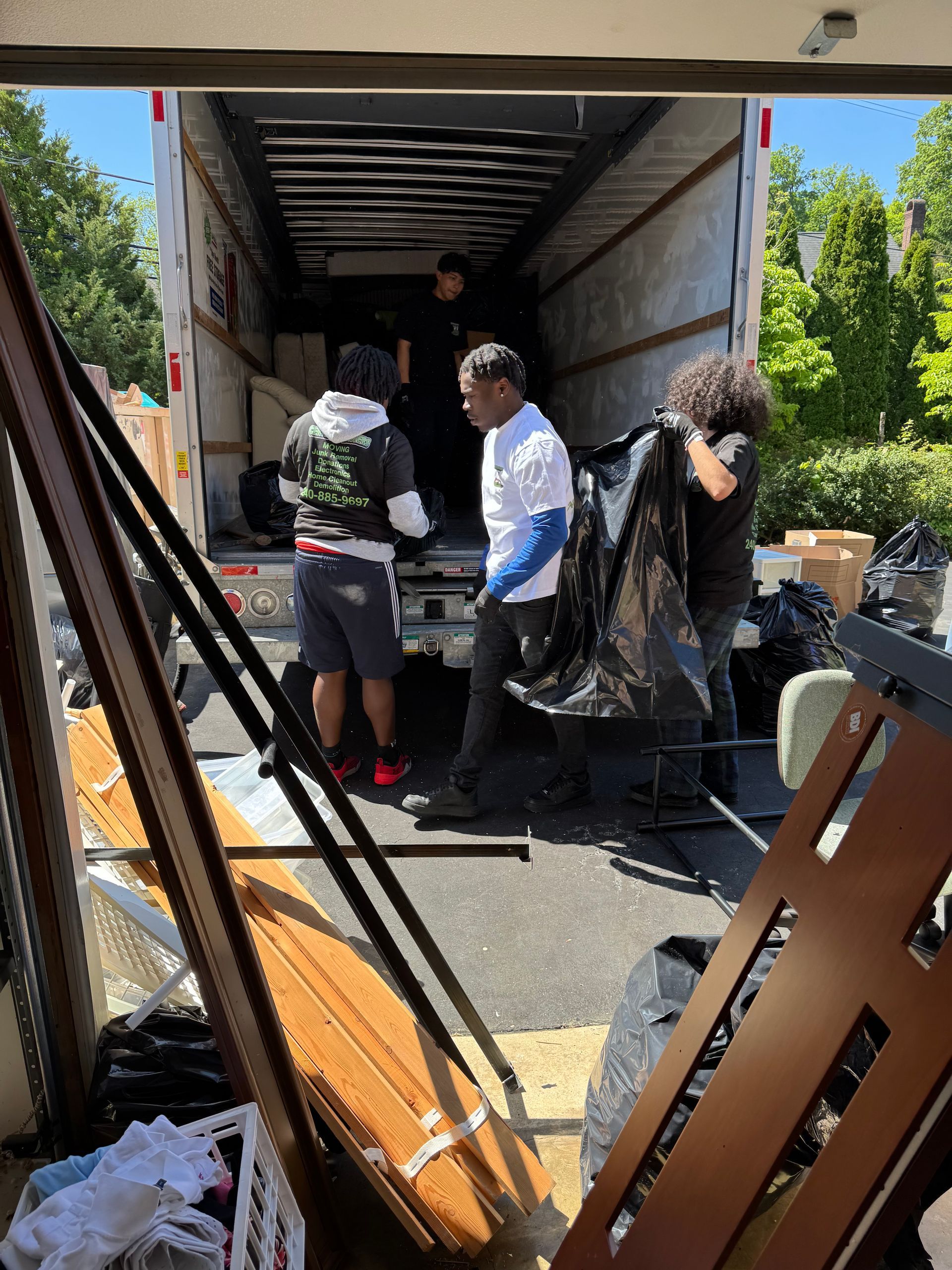 Two movers in blue uniforms loading furniture into a van.