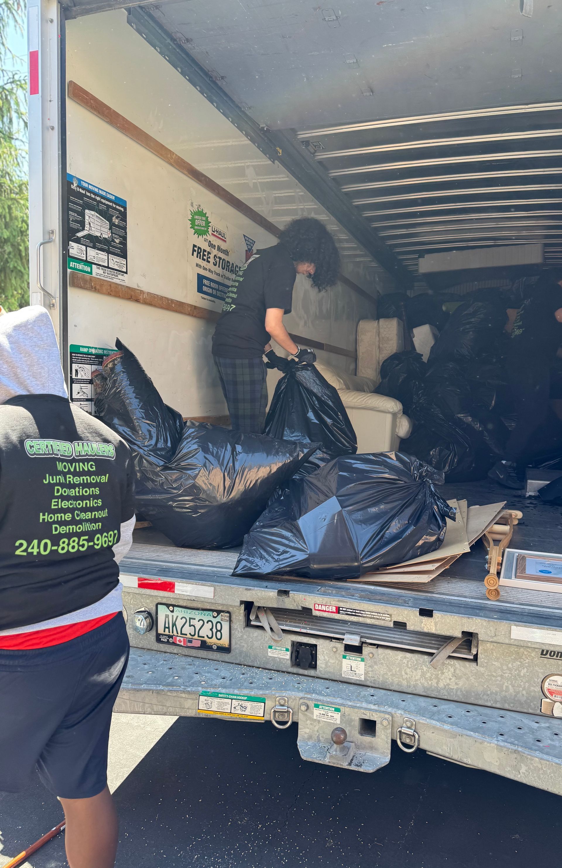 Person in orange suit operating excavator to clear brush alongside a road.