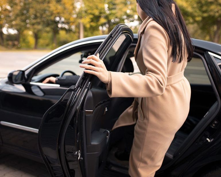 A woman in a coat is getting out of a car.