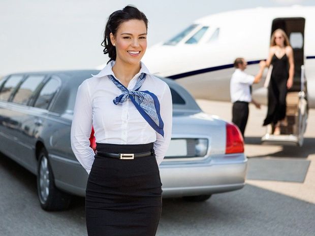 A woman is standing in front of a limousine and an airplane