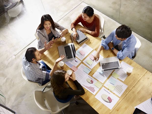 A group of people are sitting around a table having a meeting.