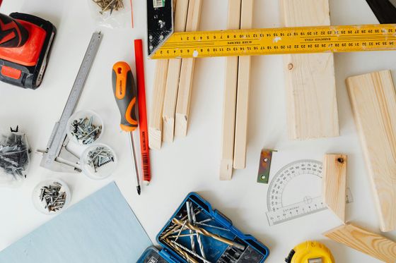 A table topped with wood , screws , measuring tape , and other tools.