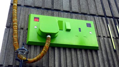 A green electrical outlet on the side of a building