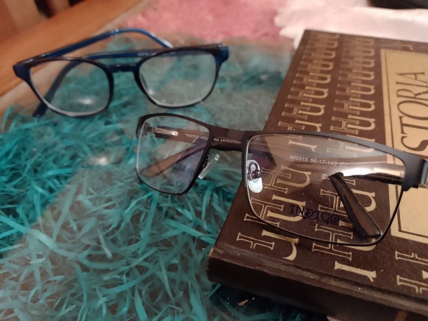 Dos pares de gafas, una negra y otra azul, descansan sobre un libro marrón