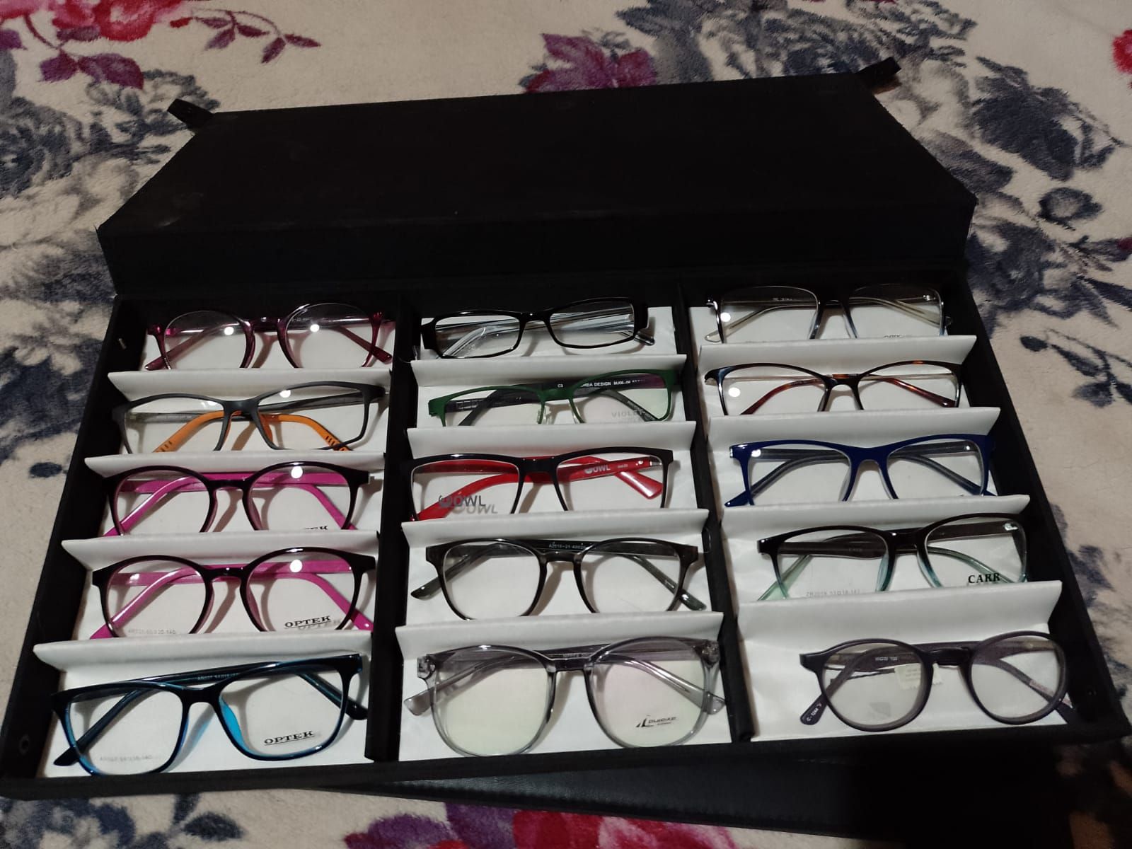 Un estuche negro que contiene quince pares de gafas graduadas de diferentes marcas