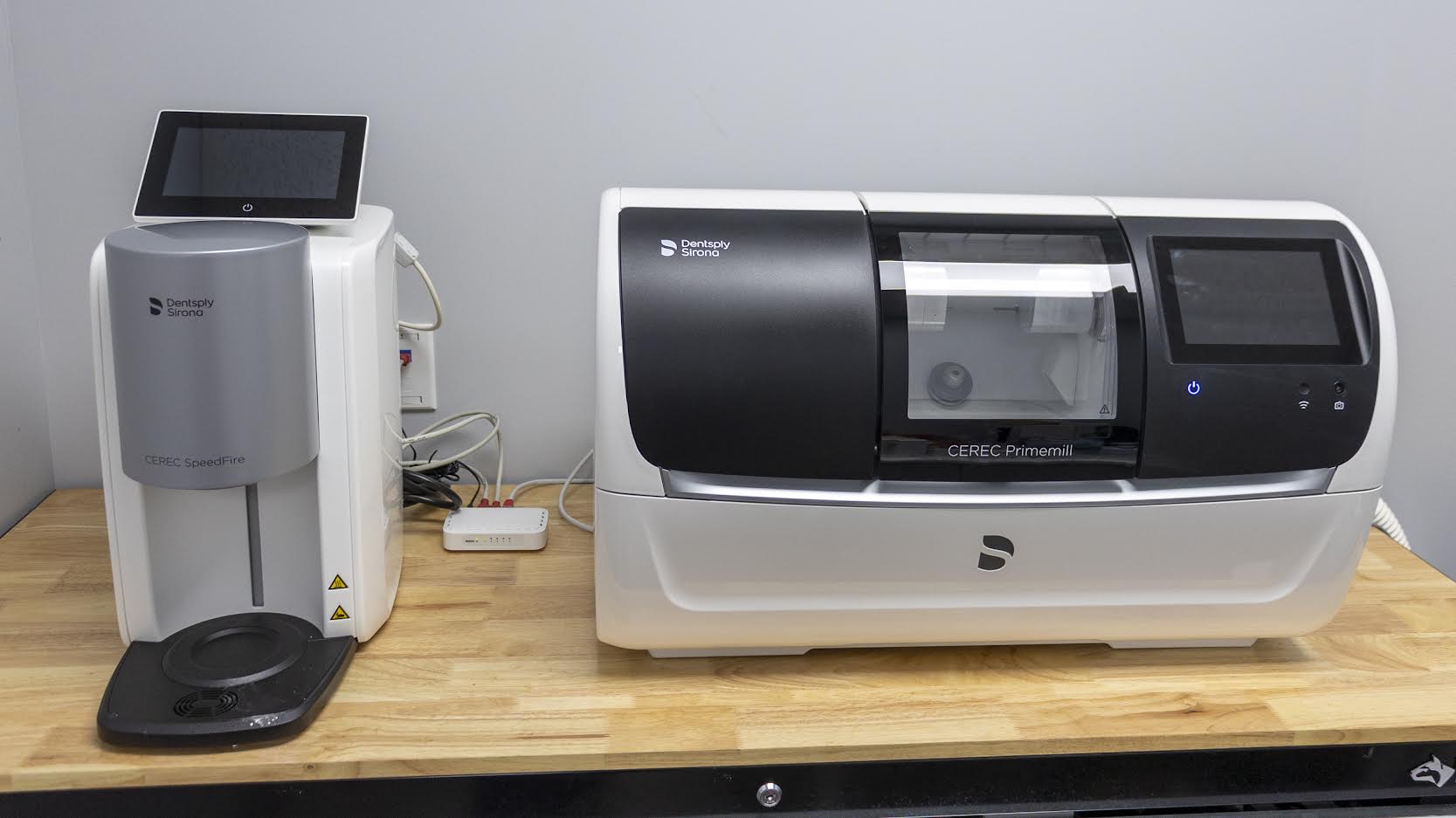 Two dental machines are sitting on a wooden table.