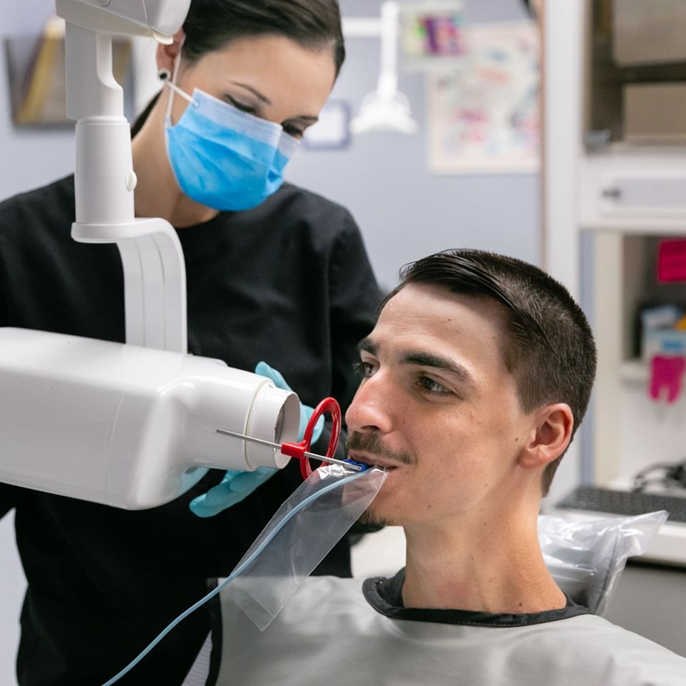 A man is getting his teeth examined by a dentist wearing a mask.