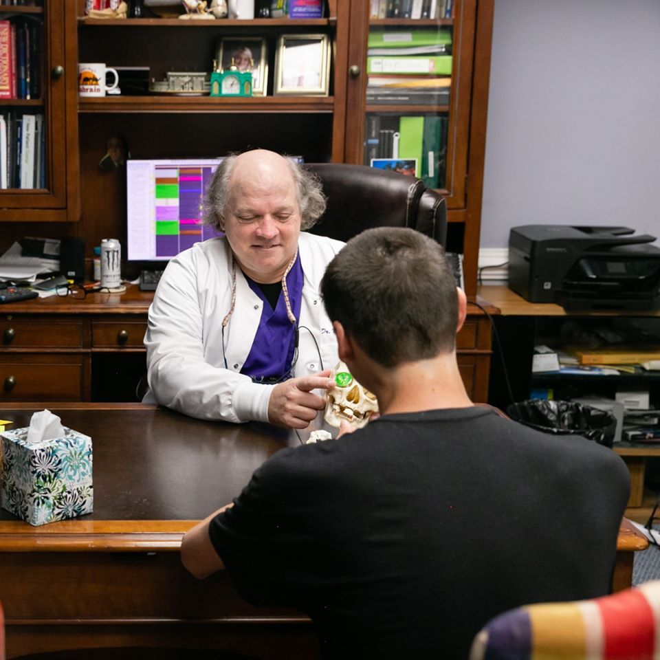 A man is sitting at a desk talking to a doctor