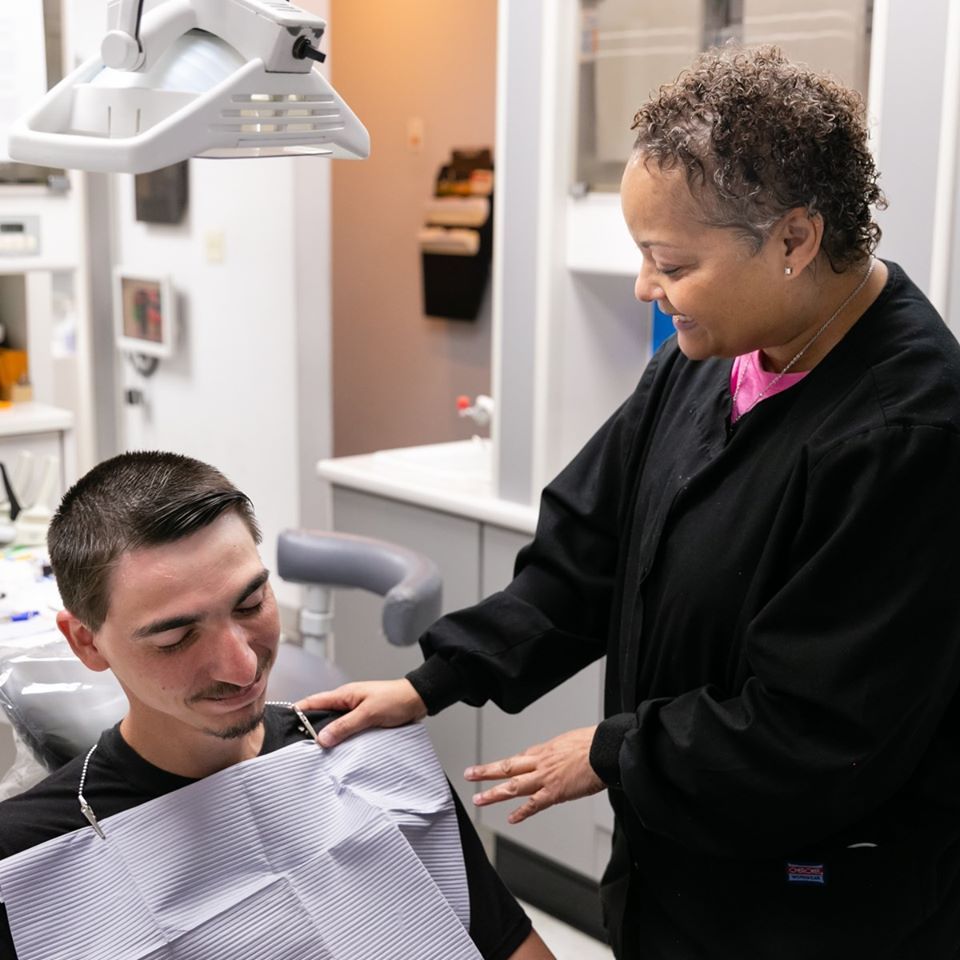 A female dentist examines a man 's teeth in a dental office