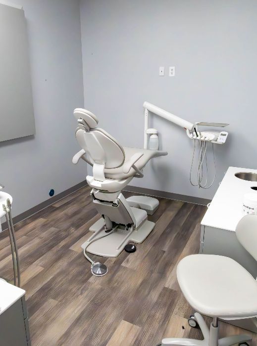 A dental office with a dental chair and a sink.