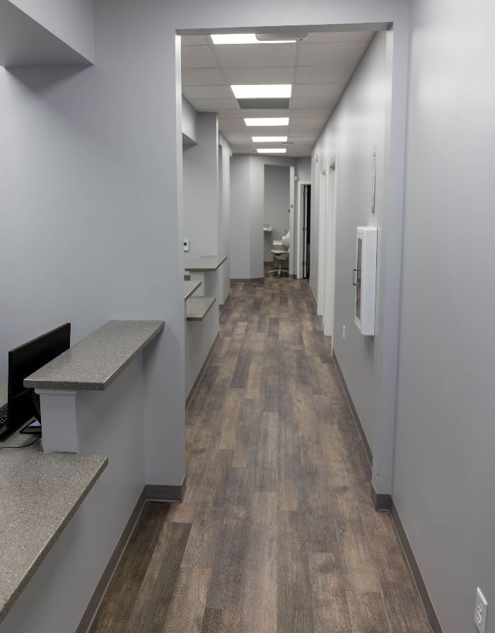 A long hallway with wooden floors and a desk in the middle.