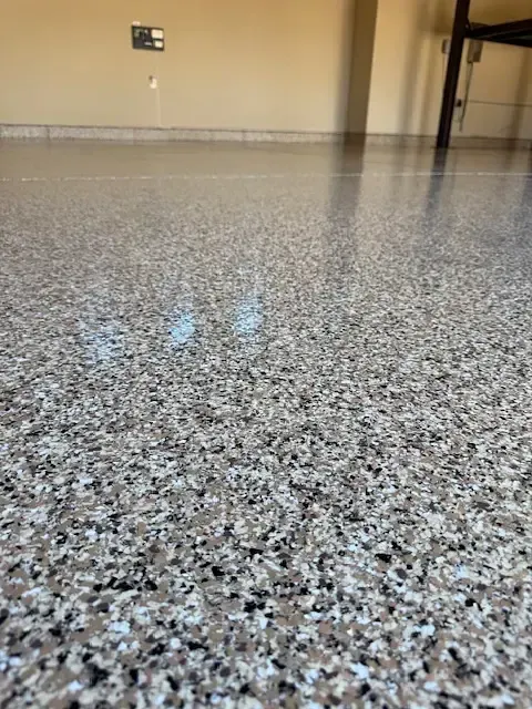 Close-up view of a speckled, gray and tan epoxy floor in a garage.