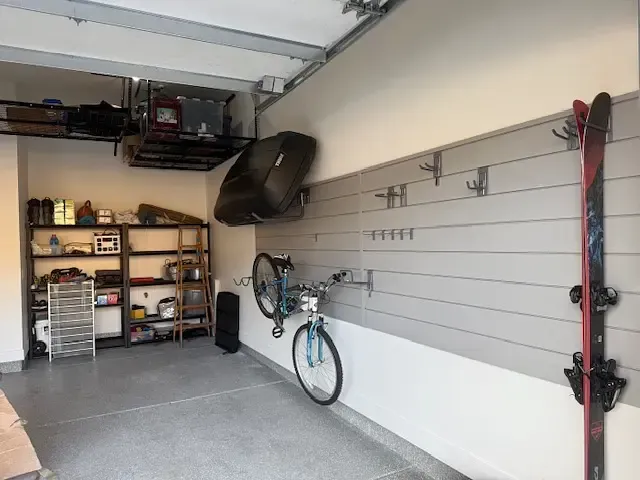 Garage with storage shelves, bike, skis, and wall-mounted accessories.
