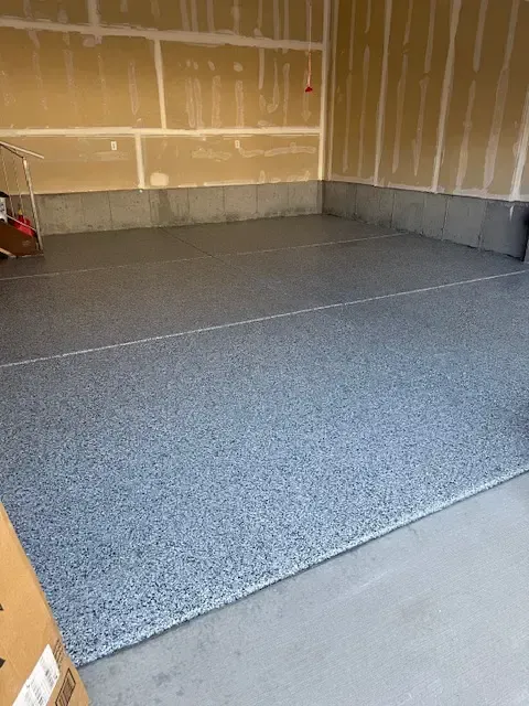 Garage with grey epoxy floor and unfinished walls.