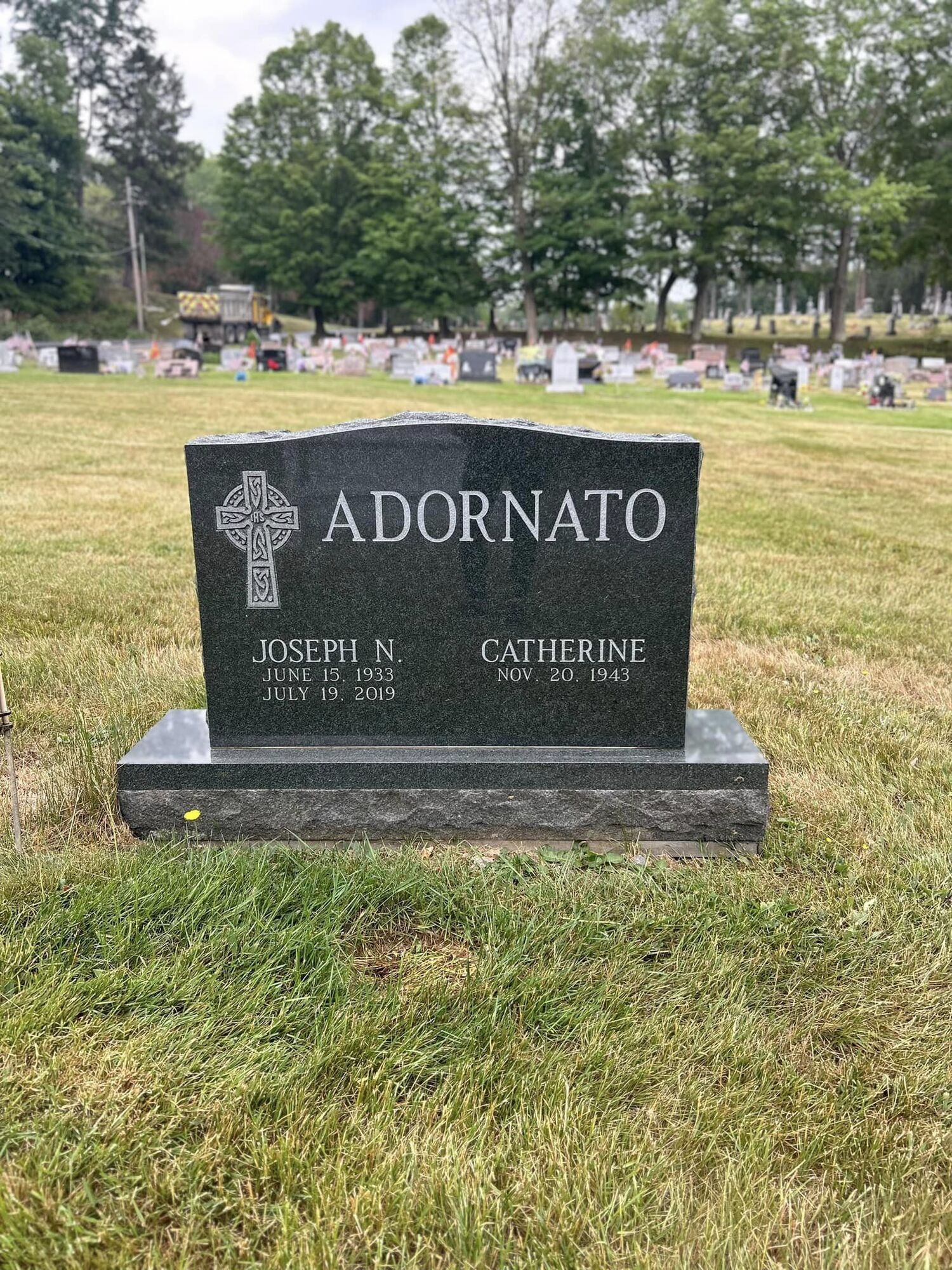 Black granite tombstone in a cemetery, inscribed 