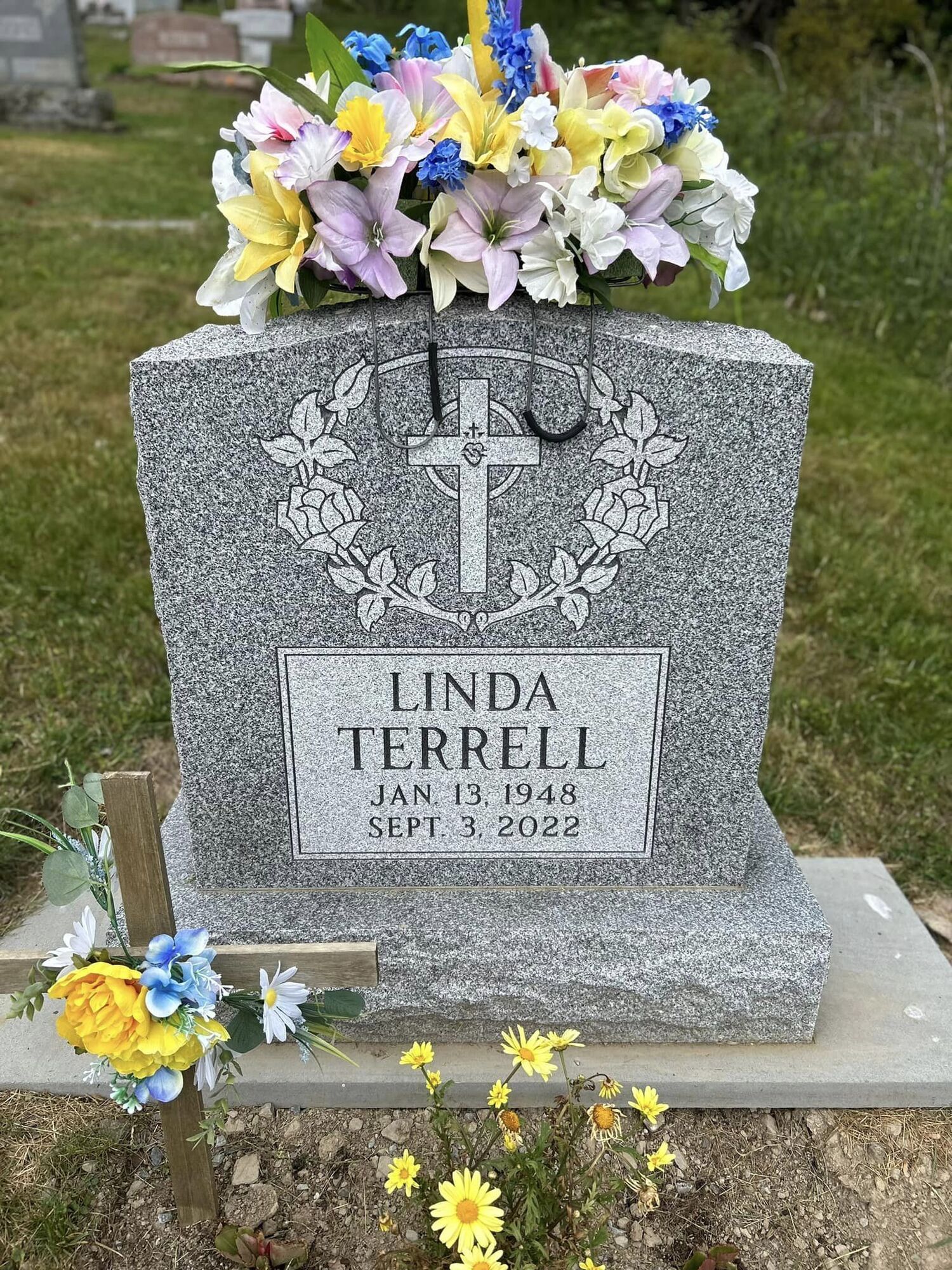 Grave marker for Linda Terrell with flowers on top and on the ground.