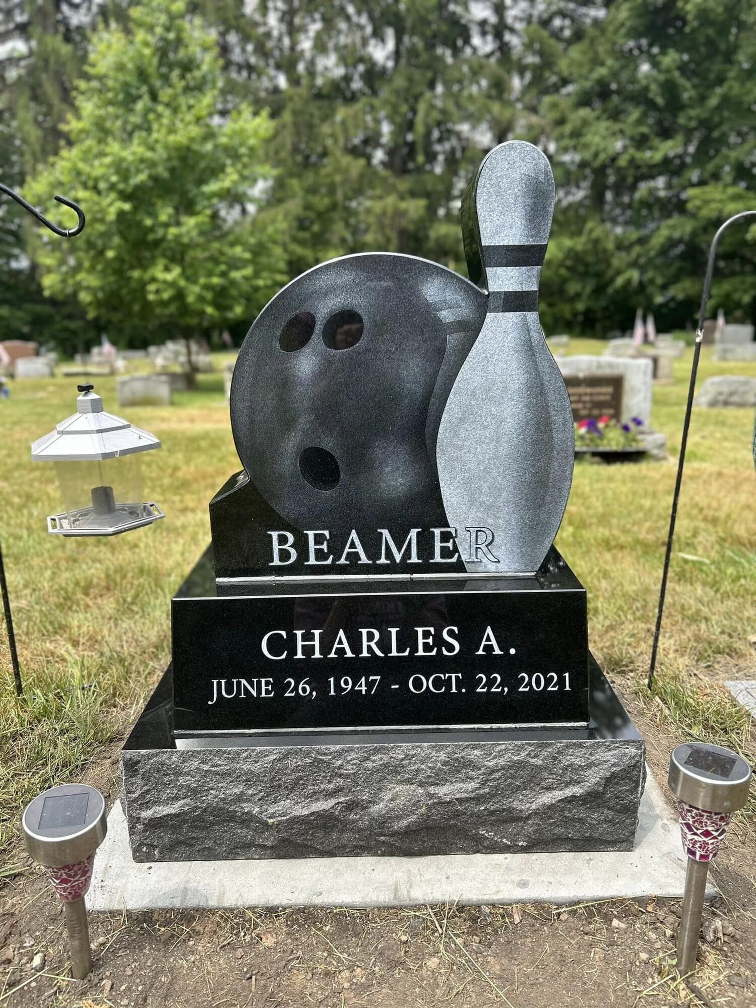 Headstone for Charles A. Beamer, featuring bowling ball and pin, in a cemetery.