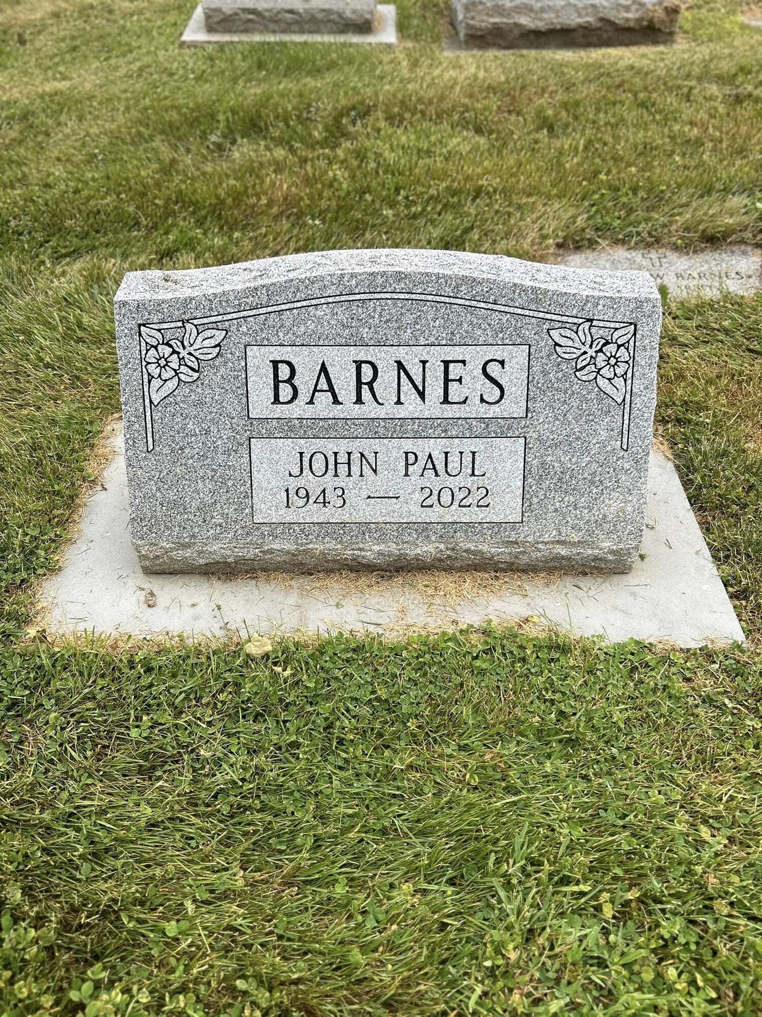 Headstone of John Paul Barnes, 1943-2022, at a cemetery, with the family name “Barnes” above.