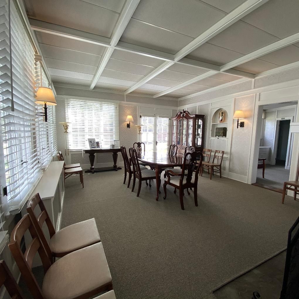 Dining room with dining table, chairs, buffet, and display cabinet; neutral colors, sunlight.