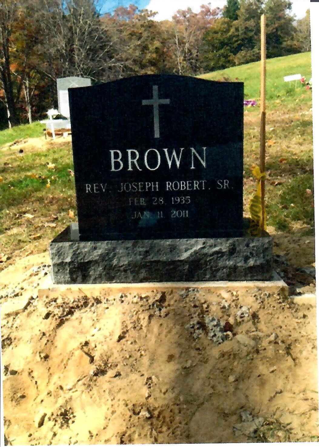 Black headstone in a cemetery, inscribed 