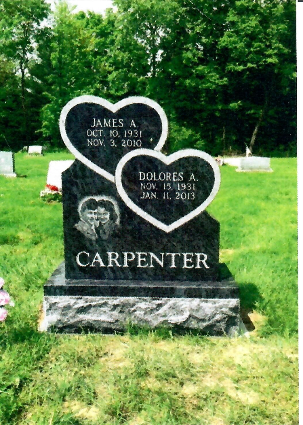 Black granite headstone with heart-shaped inscriptions for James A. (1931-2010) and Dolores A. (1931-2015), in a cemetery.