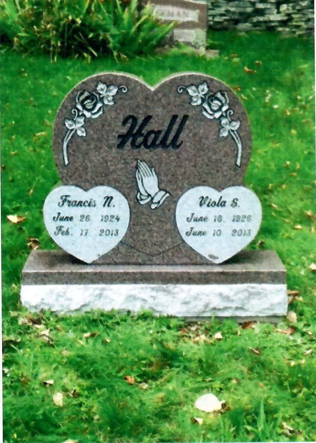 Heart-shaped headstone for Hall family, roses carved at top, dates & names on two hearts below, prayer hands in center.