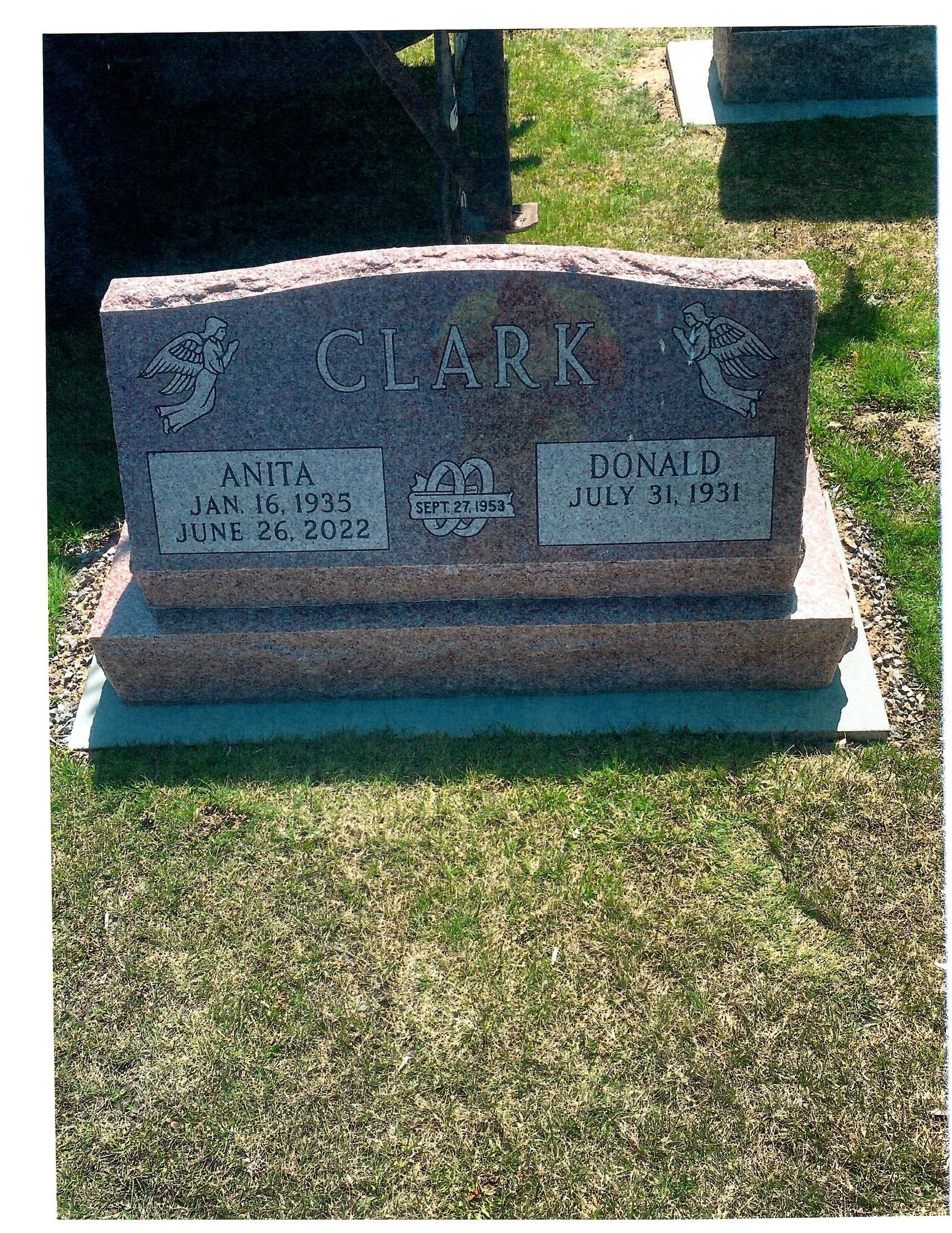 Pink granite headstone for Clark family: Anna (1935-2022) and Donald (1931-2011). Located in a grassy cemetery.