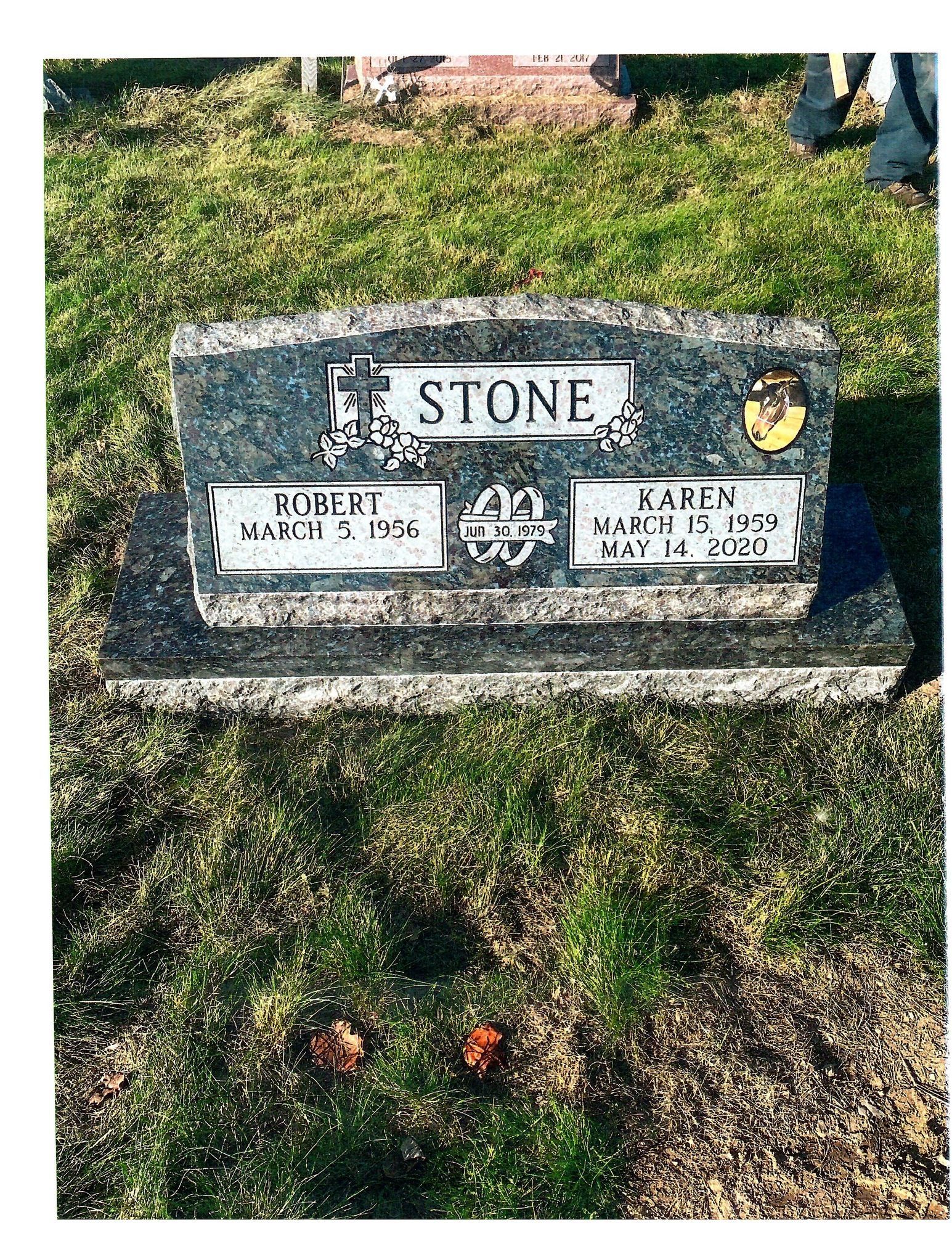 Tombstone of Robert and Karen Stone. Black granite with names, dates, and emblem on green grass.
