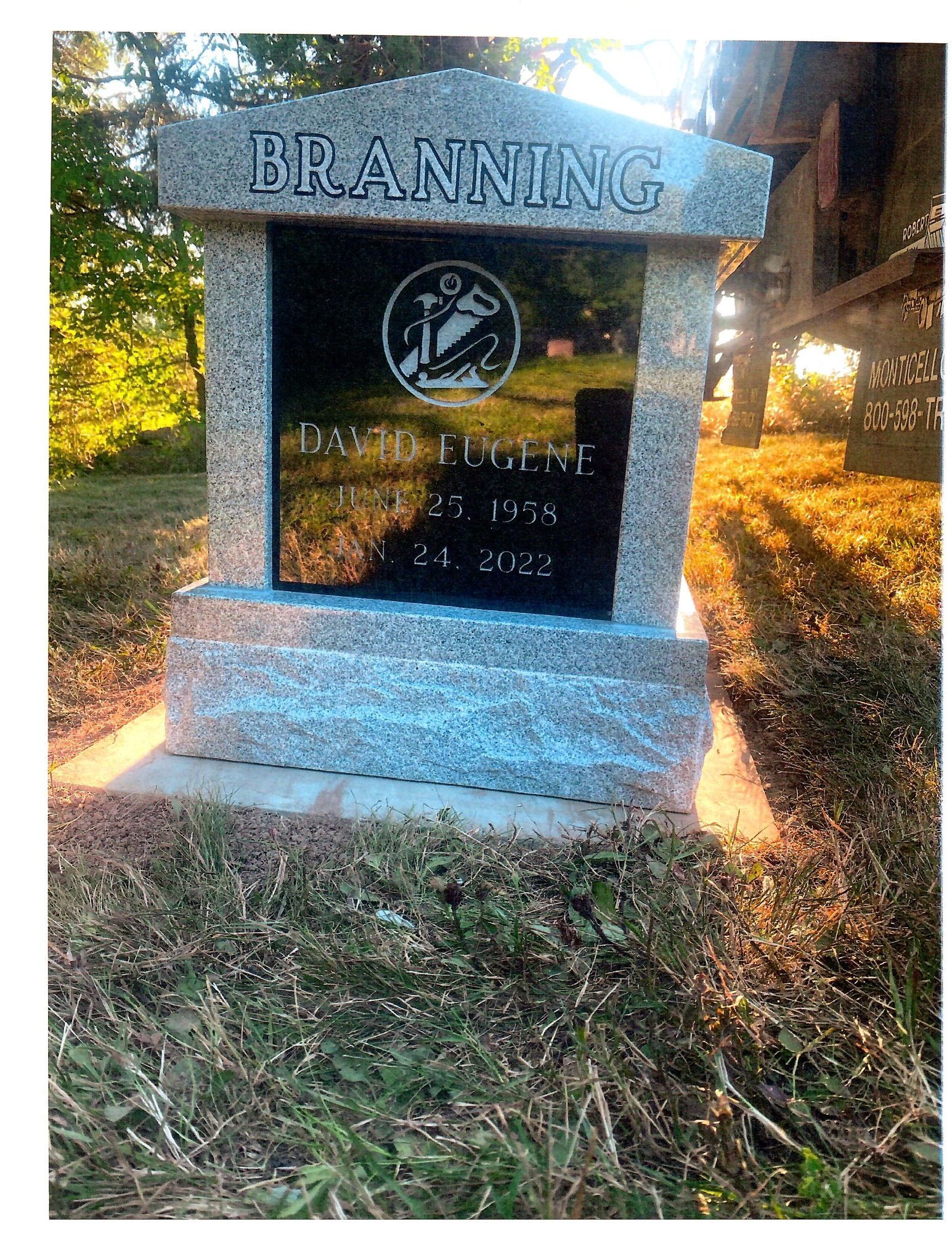 Gravestone of David Eugene Branning, 1958-2022, with an etched design, set in a grassy area.