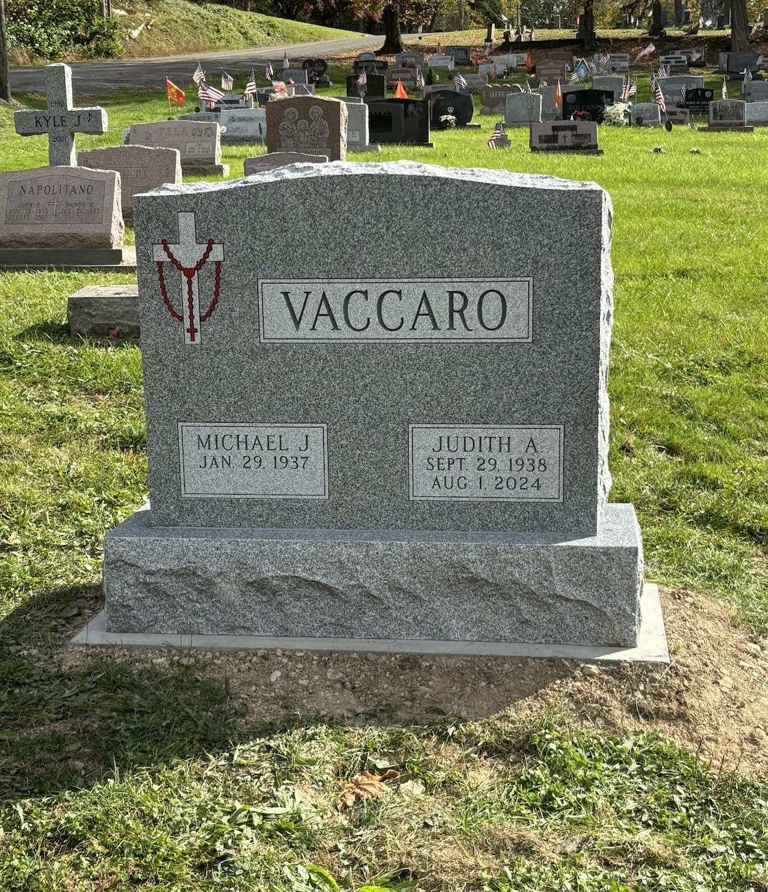 Gray granite headstone in a cemetery, inscribed with the family name Vaccaro, with birth/death dates.