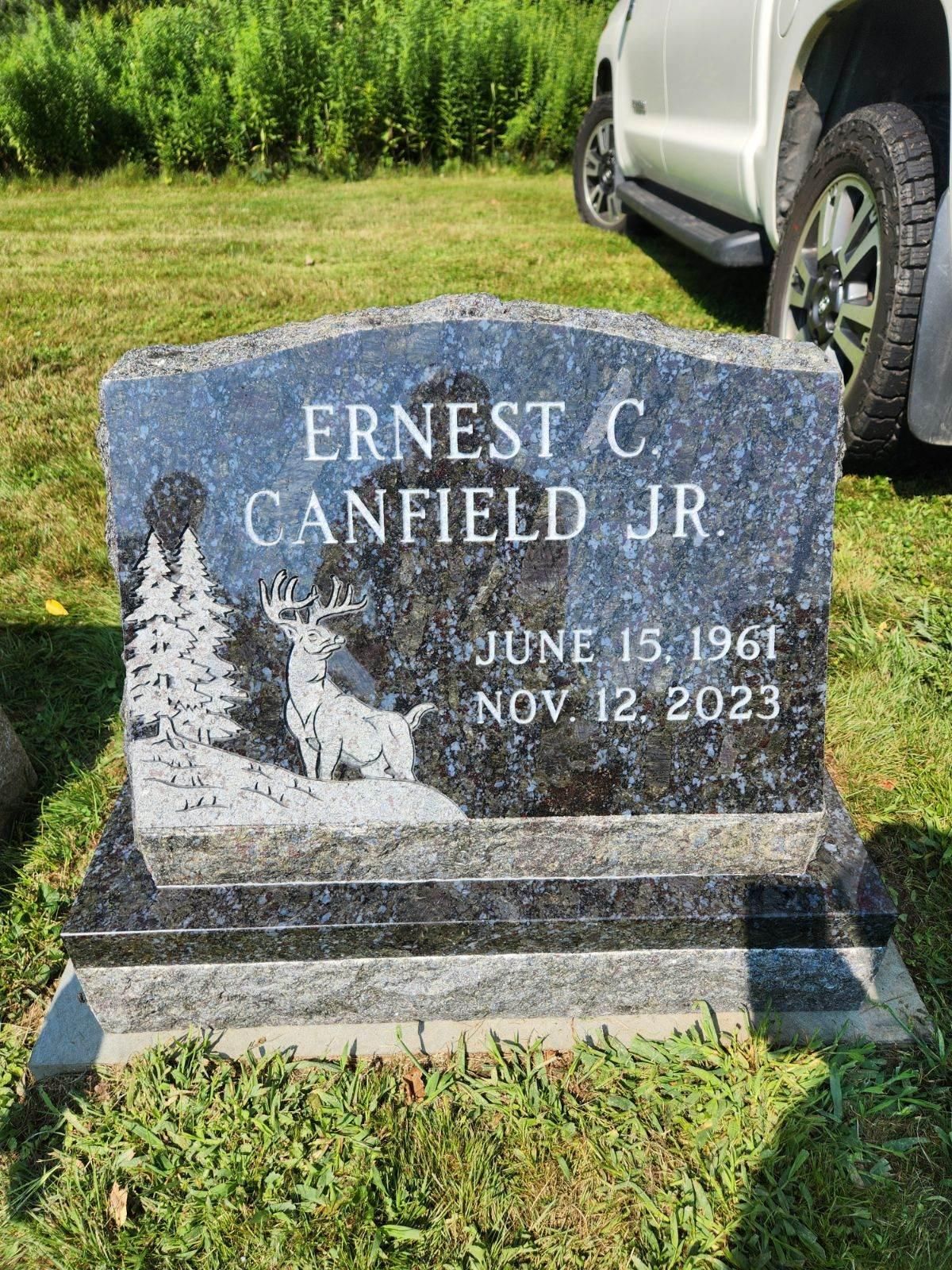 Headstone for Ernest C. Canfield Jr., born June 15, 1961, died Nov 12, 2023, with forest and deer etching.
