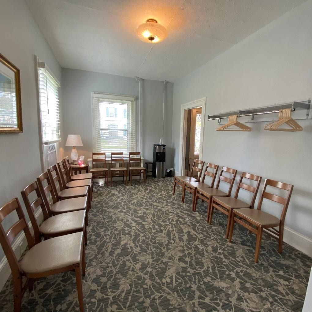 A waiting room with rows of chairs, a water cooler, and a coat rack.