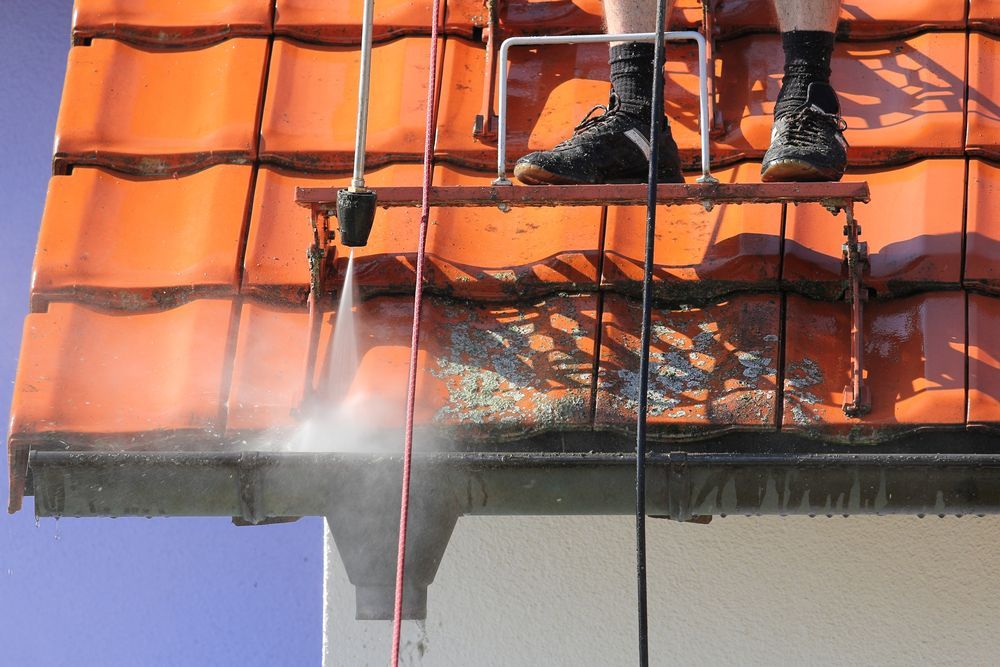 Workers Pressure Washing an Orange Tiled Roof From a Lift — A1 Roof Cleaning In Maryborough, QLD