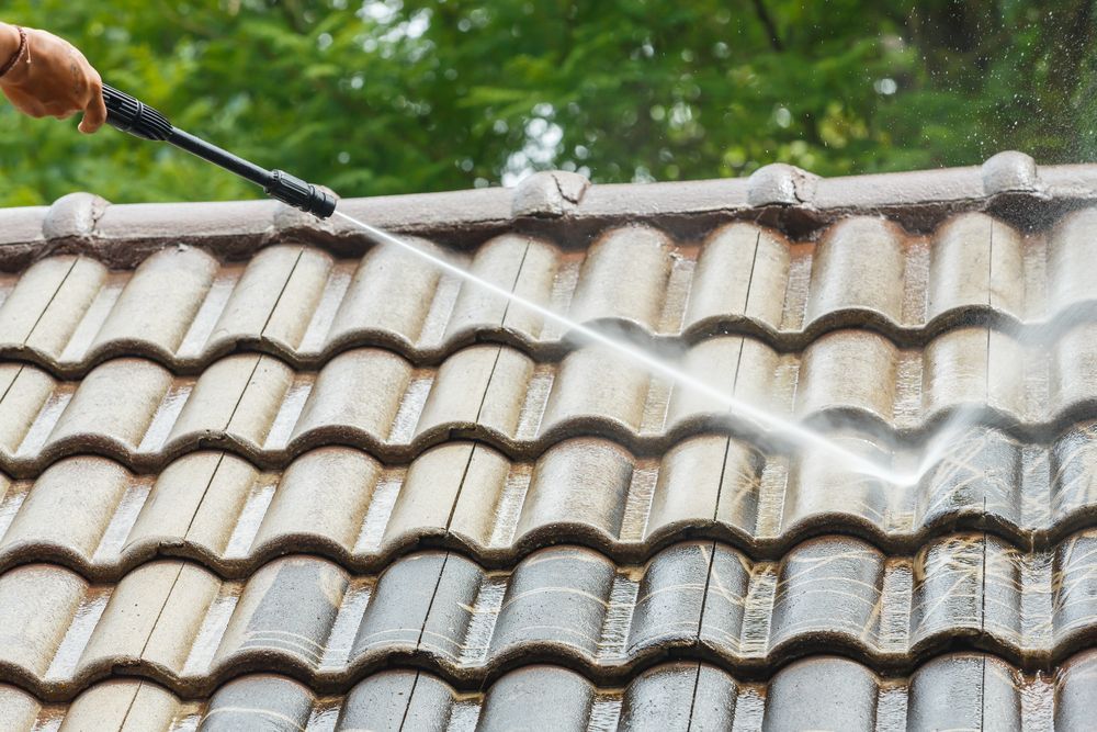 Person Pressure-washing a Gray Tiled Roof Outdoors — A1 Roof Cleaning In Maryborough, QLD