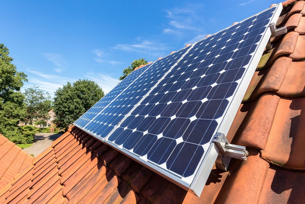 Solar Panels Mounted on a Red-tiled Roof Under a Blue Sky — A1 Roof Cleaning In Hervey Bay, QLD