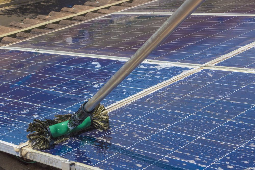 Brush Cleaning Blue Solar Panels on a Rooftop — A1 Roof Cleaning In Childers, QLD