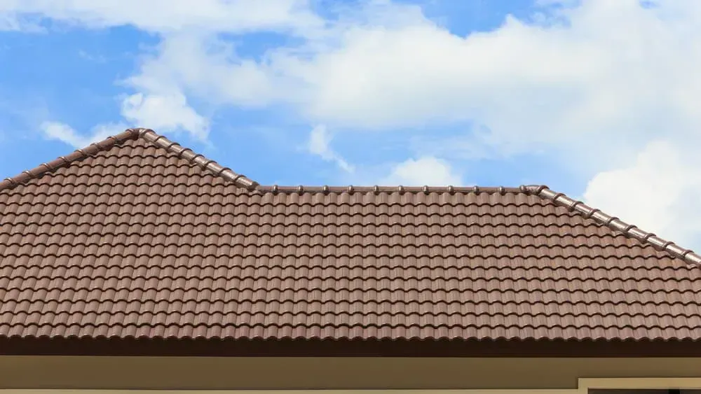 A Brown Tiled Roof Against a Blue Sky — A1 Roof Cleaning In Kepnock, QLD