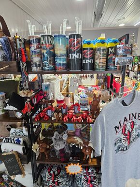 A t-shirt with maine on it is hanging on a shelf in a store.