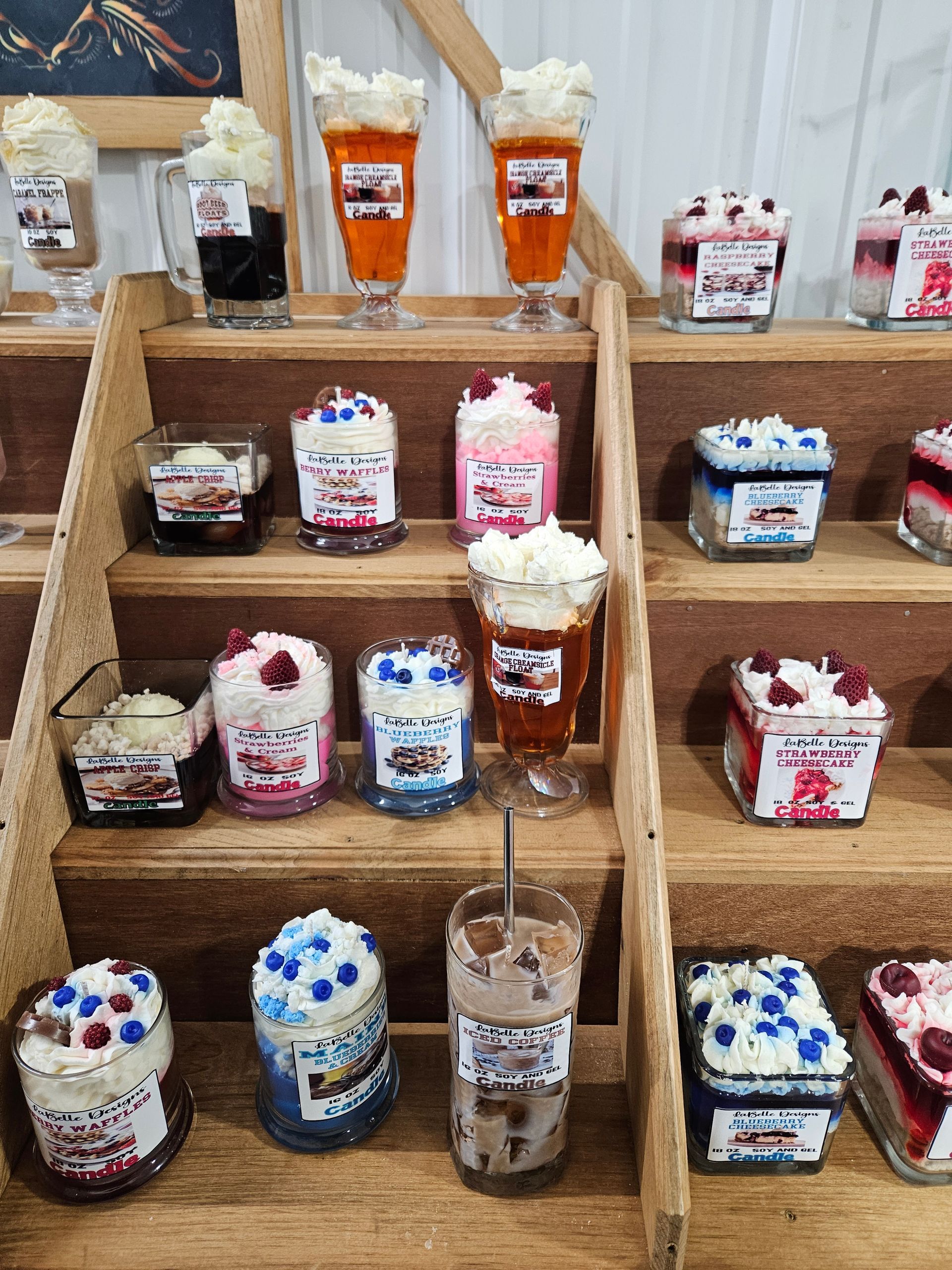 A display of candles decorated to look like desserts on a wooden shelf.