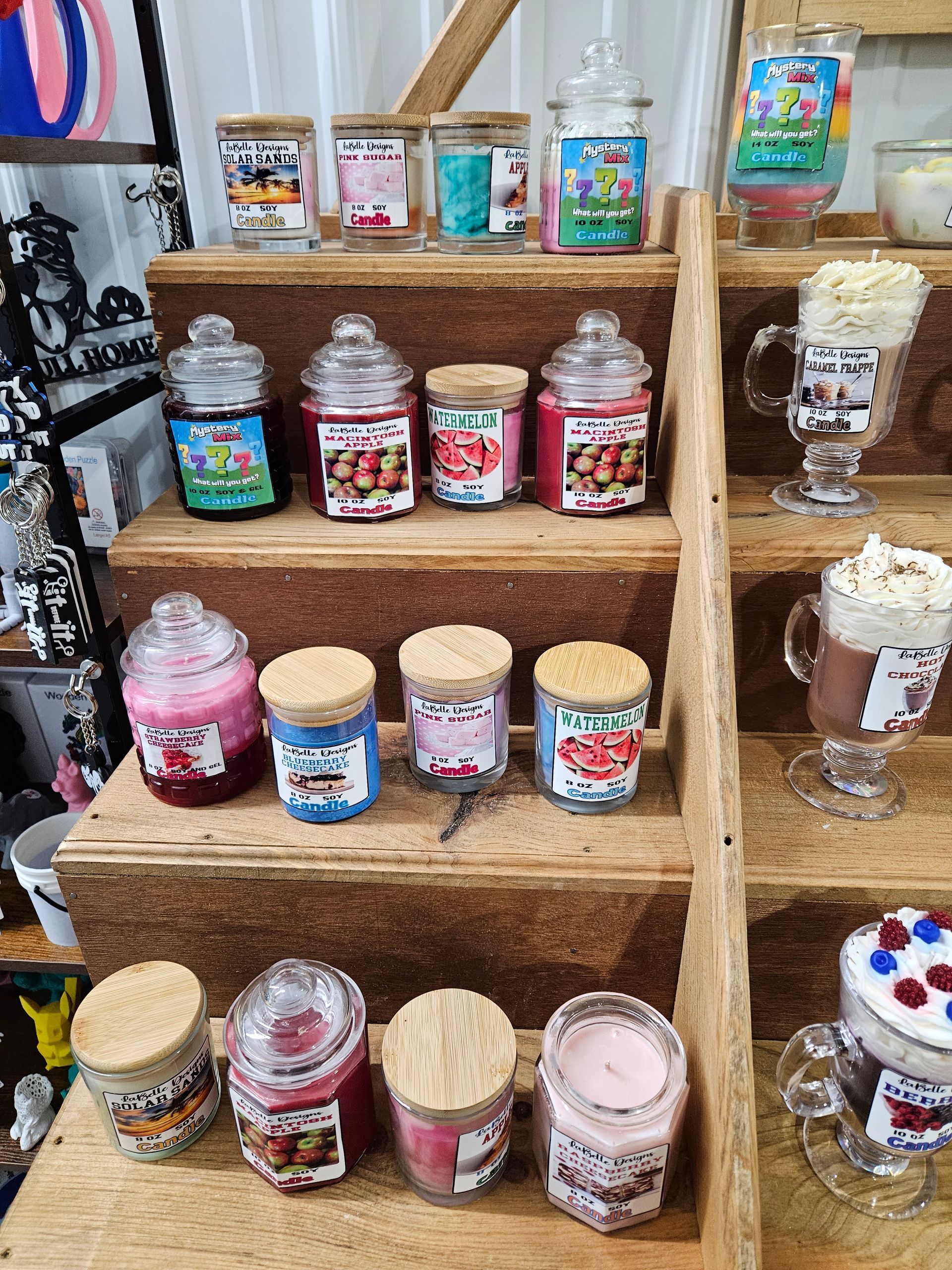 A display of candles in jars on a wooden shelf.