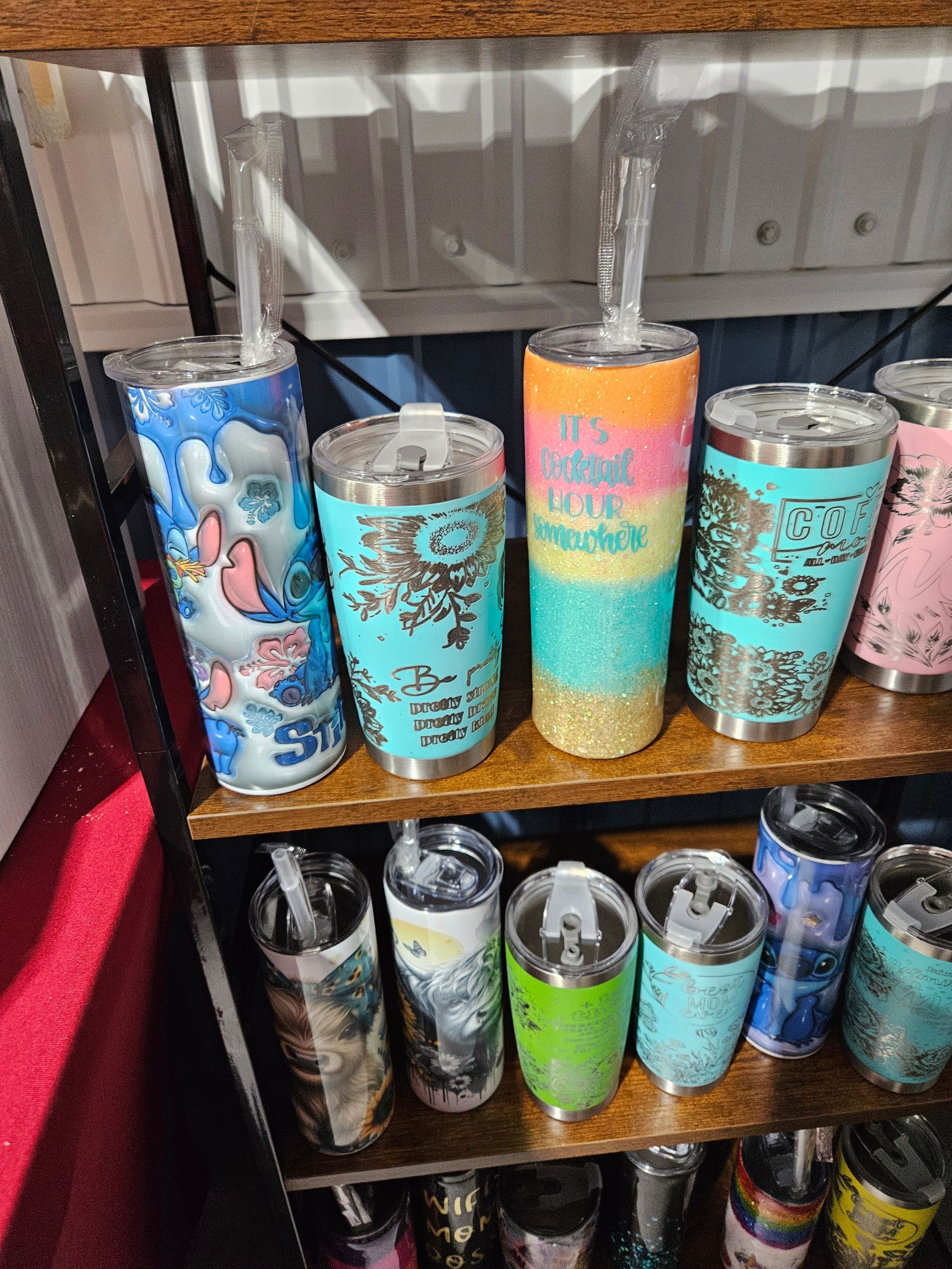 A shelf filled with a variety of stainless steel tumblers with straws.