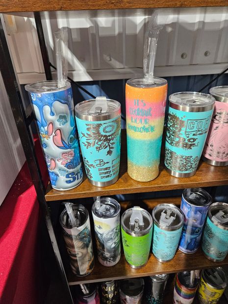 A shelf filled with a variety of stainless steel tumblers with straws.