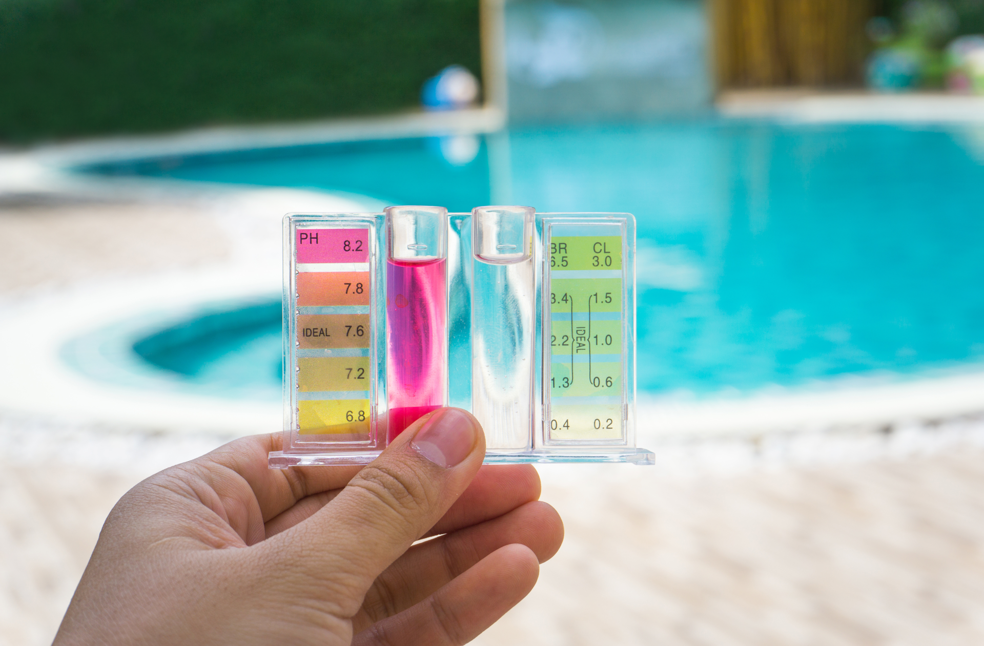 Une personne tient un tube à essai devant une piscine.