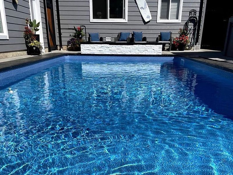 Il y a une grande piscine dans l'arrière-cour d'une maison.