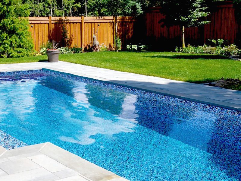 Une grande piscine dans une cour arrière avec une clôture en bois en arrière-plan