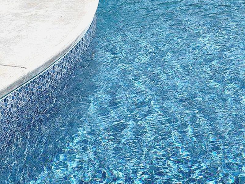 Un gros plan d'une piscine avec de l'eau bleue et une bordure blanche.