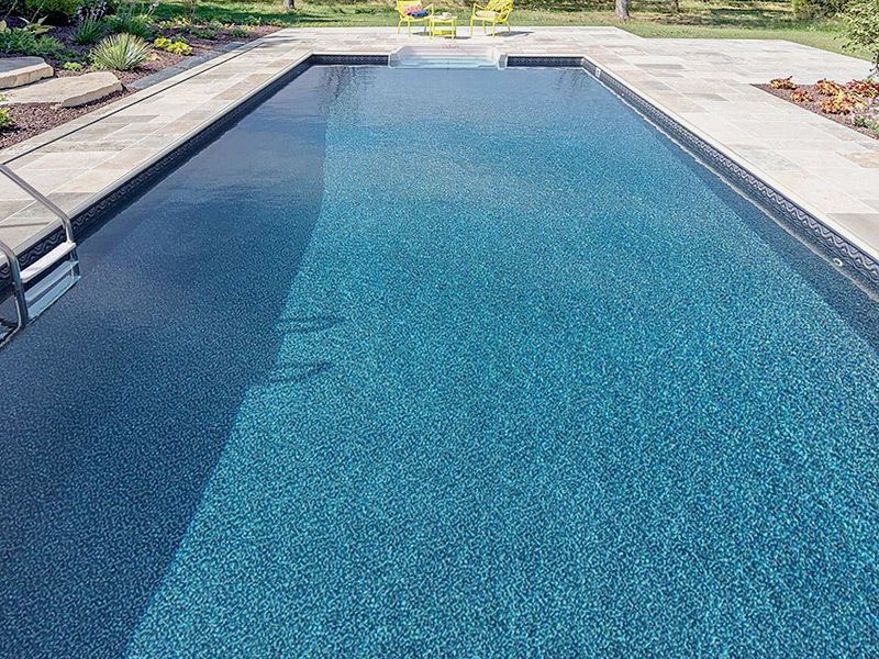 Une grande piscine avec une bordure noire et un escalier qui y mène.