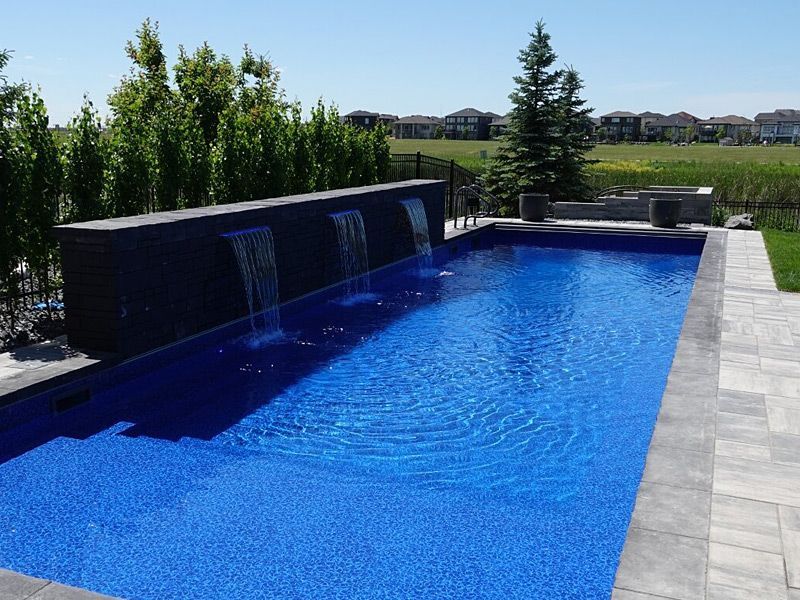 Une grande piscine avec une cascade dans l'arrière-cour