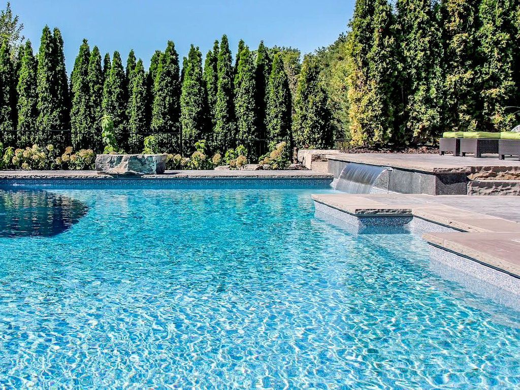 Une grande piscine entourée d'arbres par une journée ensoleillée.